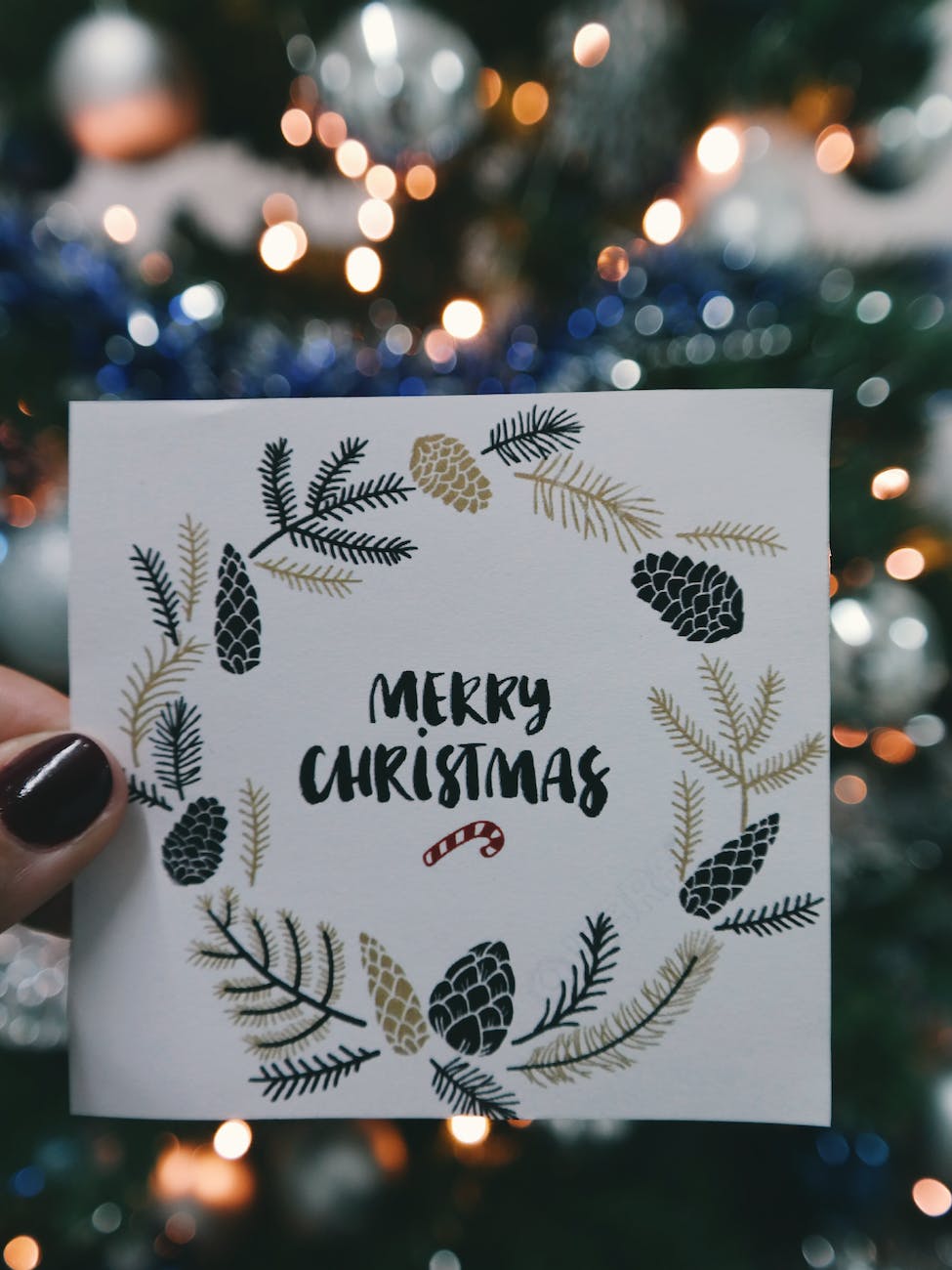person holding beige and black floral merry christmas card