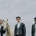 men standing with a white horse